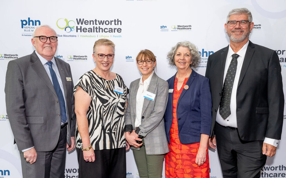 Five smiling professionals wearing name badges posing together at a Nepean Blue Mountains PHN and Wentworth Healthcare event.